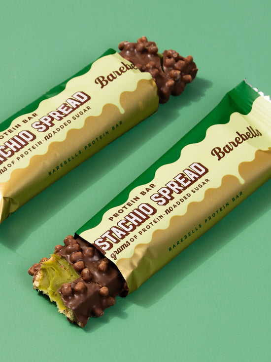 Two Barebells Pistachio Spread bars with packaging partially open displaying the product inside